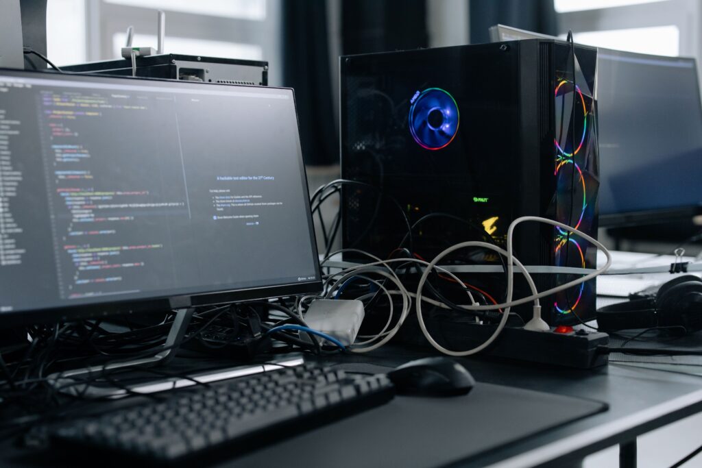 pexels-photo-6804581-6804581 A modern workspace featuring a computer monitor with code, a PC tower, and peripherals.